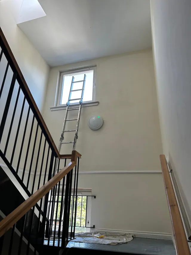 Communal stairwell repainted in a clean off-white, ladders still in place