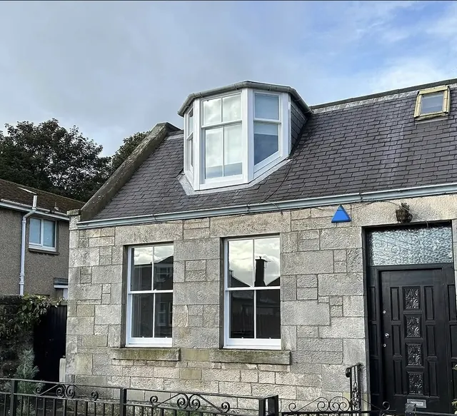 Stone cottage with freshly painted white sash windows and dormer