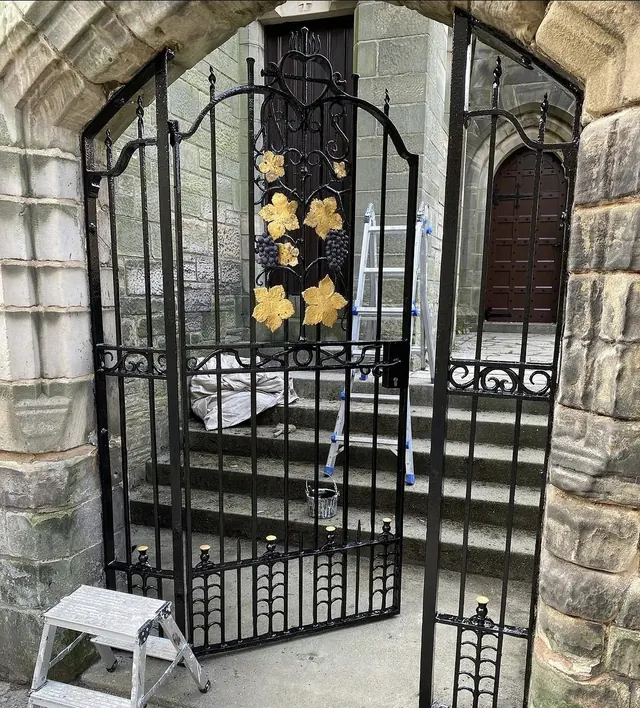 Wrought-iron church gate restored in black gloss with gilded vine leaves